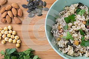 Integral rice as pilaf, cooked with almond, pumpkin seeds, chick-pea and sprinkled with parsley on wooden background.