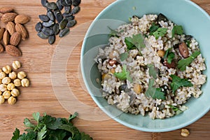 Integral rice in a bowl cooked with almond, pumpkin seeds, chick-pea and sprinkled with parsley on wooden background.