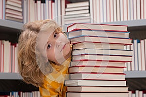 Intellectual child, clever pupil. School child studying in school library. Kid reading book in library on bookshelf