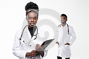 Intellectual healthcare professional afro american doctor with collegue with clipboard isolated on white background