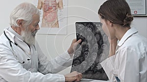 Intellectual healthcare professionals with white labcoat, looking at full body x-ray radiographic image, ct scan, mri