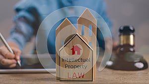 Intellectual property law concept. Wooden home with Intellectual property law word and a gavel on a desk