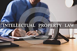 Intellectual property law. Jurist working at table in office, focus on gavel photo