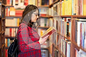 Intellectual Teenage girl choose books and pick them from a library or bookstore.