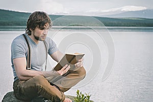 Intelligent man reading book outdoor lake and mountains landscape