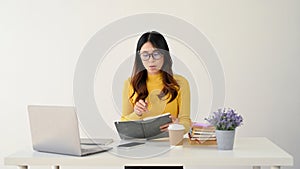 An intelligent and nerdy Asian female college student in glasses focused on reading a book