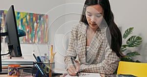 Intelligent woman working in financial analysis marketing calculates company profits sits in office fills in charts