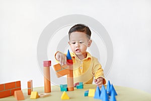 Intend asian little boy playing a wood block toy on table over white background