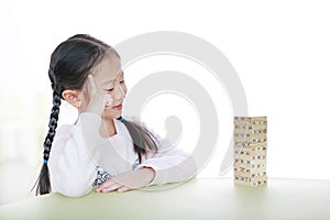 Intend little Asian child girl thinking to playing wood blocks tower game for Brain and Physical development skill in a classroom