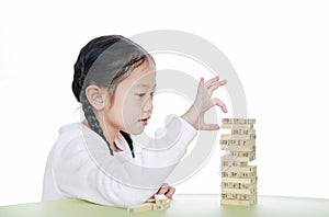 Intend little Asian child girl thinking to playing wood blocks tower game for Brain and Physical development skill in a classroom