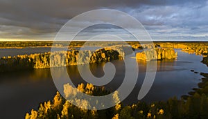 Intense bright sunrise light over lake and autumn colored trees