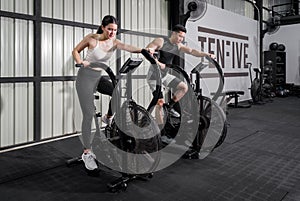 Intense Fitness Session. Two dedicated individuals pedaling on stationary exercise bikes in a modern, well-equipped gym, working