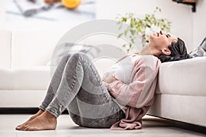 Intense menstruation pain freezes a woman sitting on the floor at home