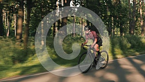 Intensive cycling training. Woman hard training on road bicycle at sunrise. Cyclist intensively pushing pedals on bicycle, sprinti