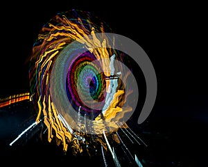 Intentional camera movement, slow shutter Zoom blur image of giant Ferris wheel illuminated and spinning at night in a fun fair