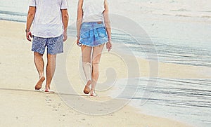 Intentionally grainy image - pencil drawing effect. A couple walking along a beach on a bright sunny day.