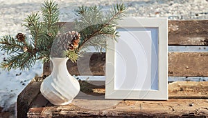 inter still life. Horizontal white frame mockup on vintage wooden bench, table. Modern white ceramic vase with pine tree branches