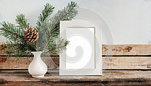 inter still life. Horizontal white frame mockup on vintage wooden bench, table. Modern white ceramic vase with pine tree branches