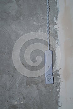 Intercom phone receiver on gray concrete background. handset hanging on the wire
