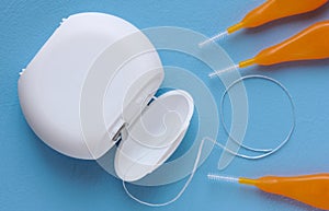 Interdental brush and floss for interdental spaces on blue background