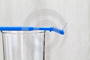 Interdental brush on glass on blurred wooden background in bathroom