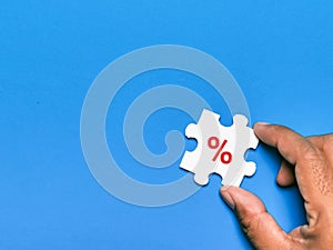 Interest rate or percentage concept. Hand hold jigsaw puzzle piece with percentage icon.
