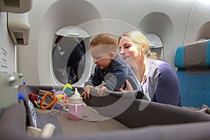 Interest to special baby bassinet during the flight.  Infant plays on mother hands at the airplane.  Travelling with mom