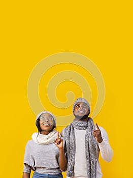 Interested african american man and woman pointing fingers upwards