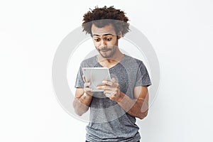 Interested african man looking at tablet over white bakground. Copy space.