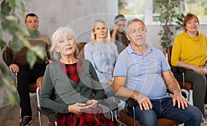 Interested aged man and woman listening to lecture in auditorium