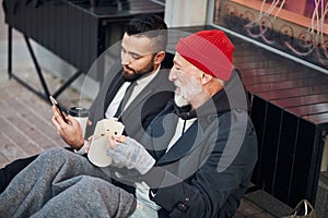 Interested beggar look at phone