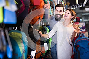 interested couple examining rucksacks in sports equipment store