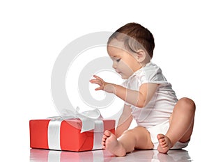 Interested curious baby in jumpsuit with gift box