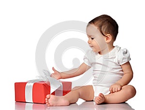 Interested curious baby in jumpsuit with gift box