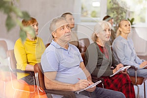 Interested elderly man listening lesson during language courses