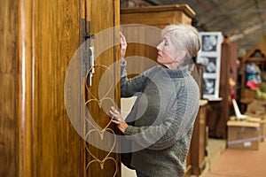 Elderly woman looking for wooden wardrobe in furnishing store