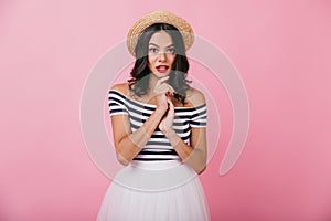 Interested glamorous woman in vintage summer attire standing on pink background. Photo of fascinati