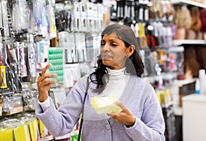 Interested Latina choosing hair rollers in cosmetics boutique