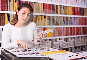 Interested Latina looking at palette of hair colors in cosmetics store