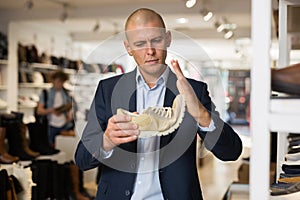 Interested man checking softness of sole of moccasins in shoe store