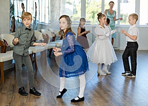 Interested preteen pupils rehearsing twist dance steps in classroom