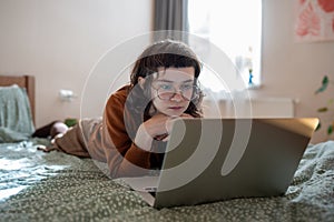 Interested teen girl spending weekend, pastime at home, watching video, film on laptop computer