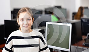 Interested teenage girl student standing in information technology classroom