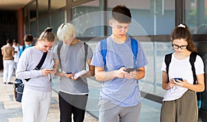 Interested teenagers using phones on college campus