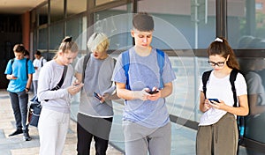 Interested teenagers using phones on college campus