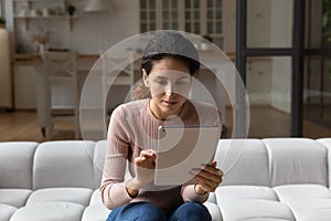 Interested young hispanic woman using digital computer tablet.