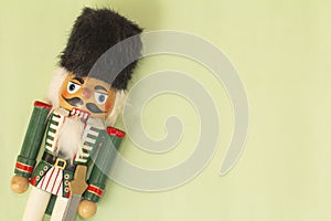 Interesting beautiful christmas nutcracker soldier on green colored paper surface texture with copy space
