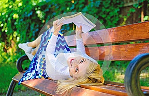 Interesting book. Lady smiling face enjoy rest. Girl reading outdoors while relaxing on bench. Girl lay bench park