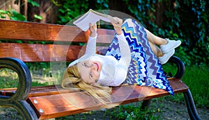 Interesting book. Smart and pretty. Smart lady relaxing. Girl lay bench park relaxing with book, green nature background