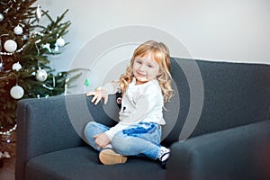 Interesting little girl sits on chair. Merry Christmas and Happy New Year. Lovely baby enjoy christmas. Childhood memories. Little
